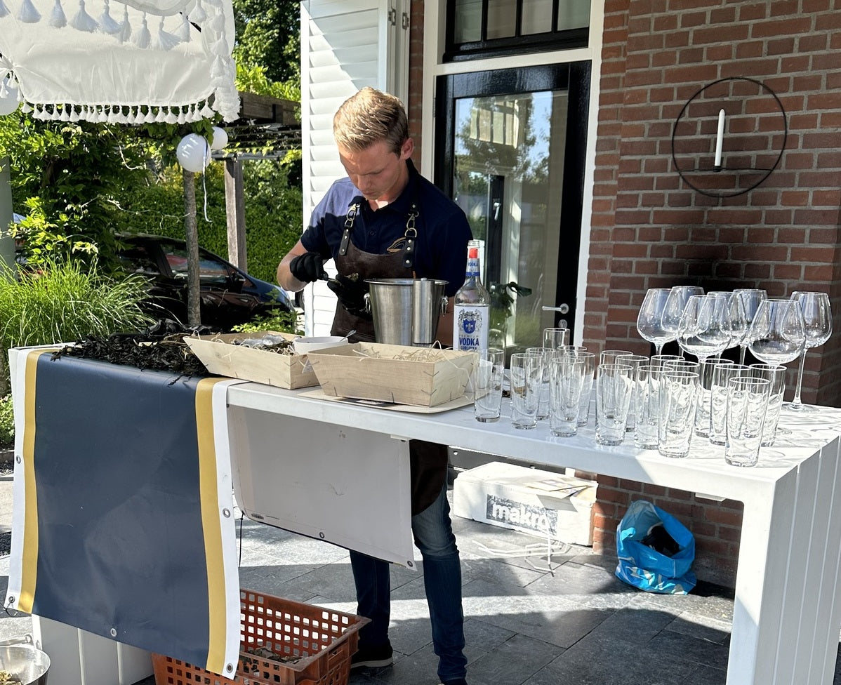 Een oesterman van ACE Oysters aan het werk op een privéfeest die oesters open aan het steken is voor de gasten van het feest